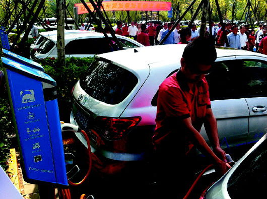 20日,省内首家纯电动汽车分时自助租赁项目在青岛启动,图为工作人员在为电动汽车充电。